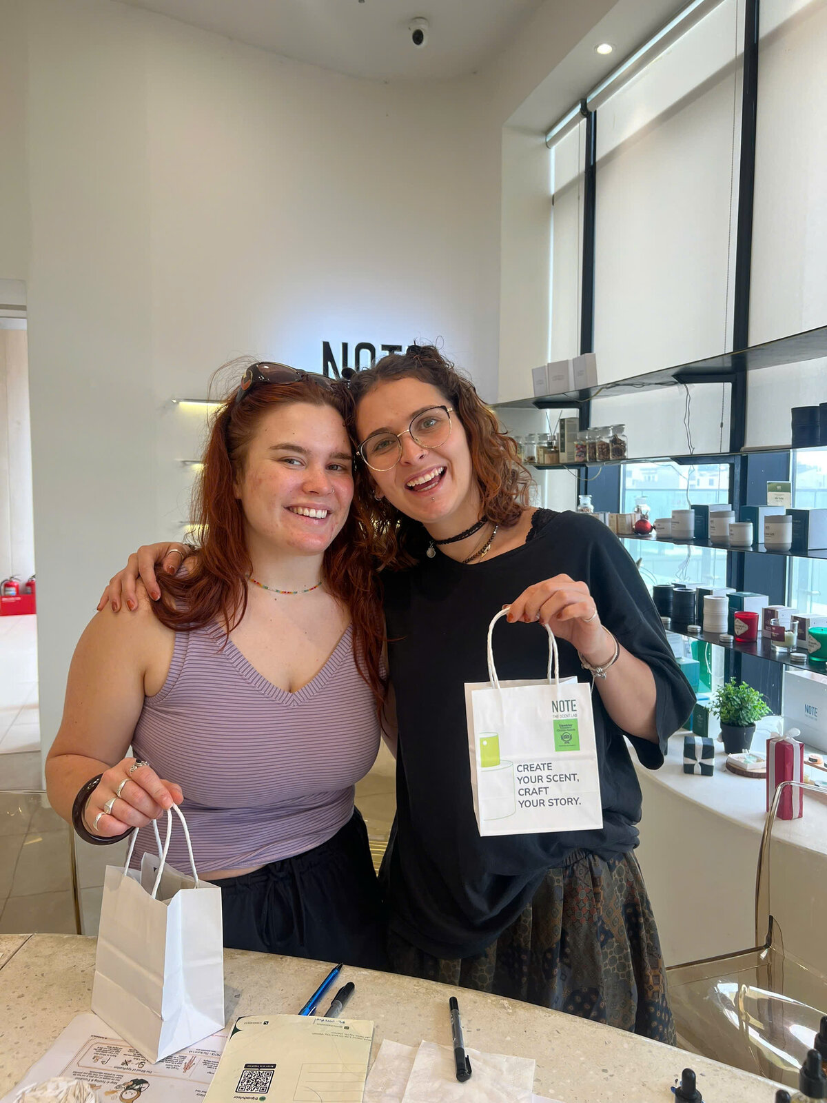 Happy visitors holding their finished custom perfume bottles at NOTE The Scent Lab Lotte Mall West Lake Hanoi workshop